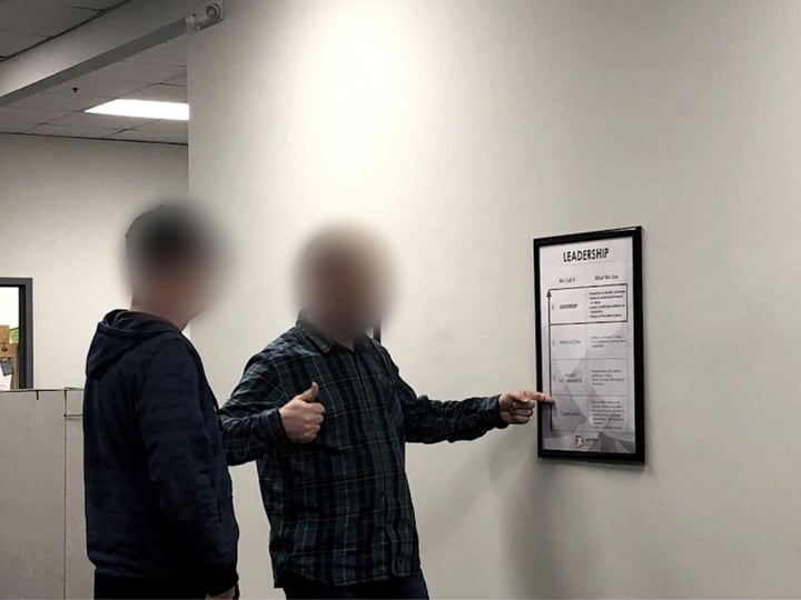A manager walking a teammate through the leadership scale posted on the wall